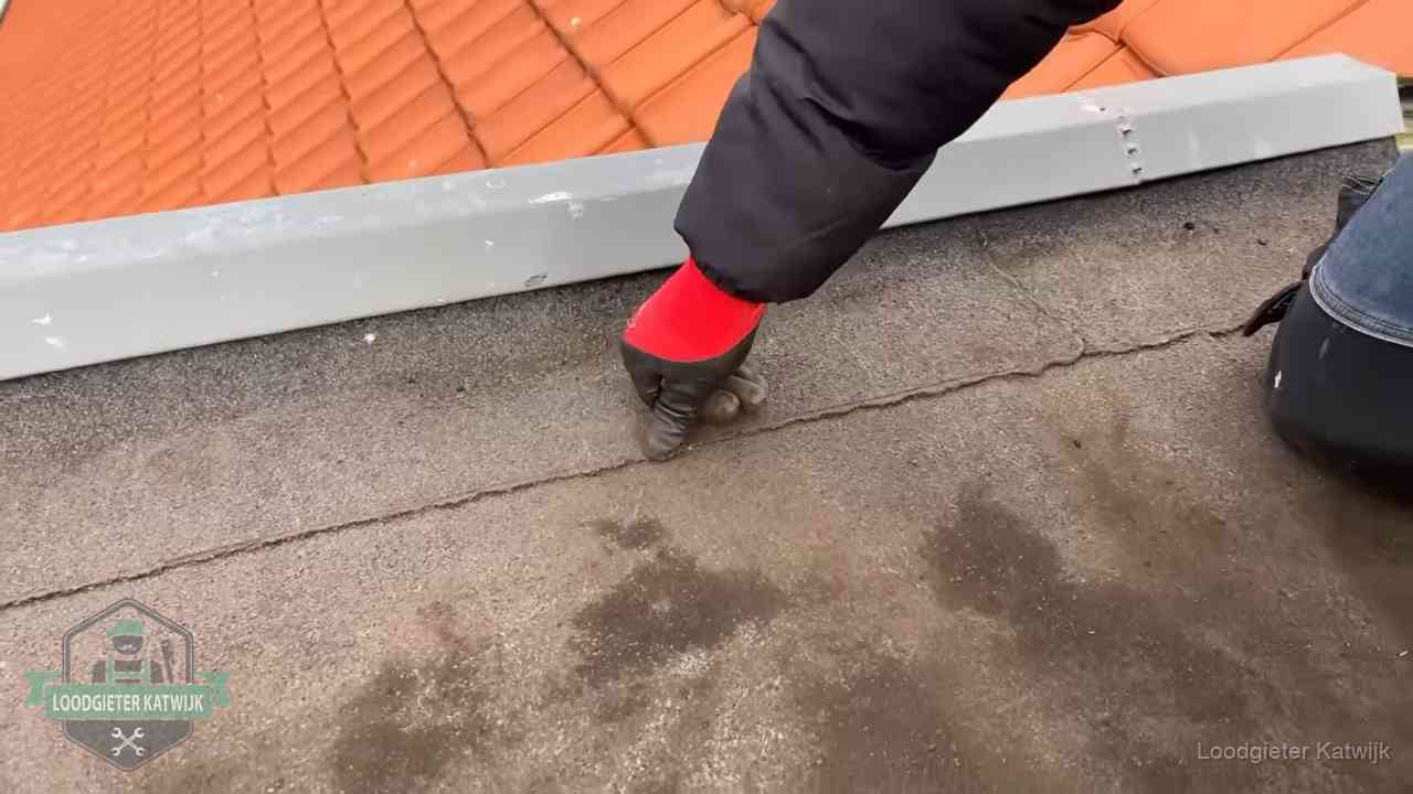 Lekkage bij de naad van een plat dak in Katwijk Vakman wijst een naad met vochtplekken aan op een bitumen plat dak in Katwijk