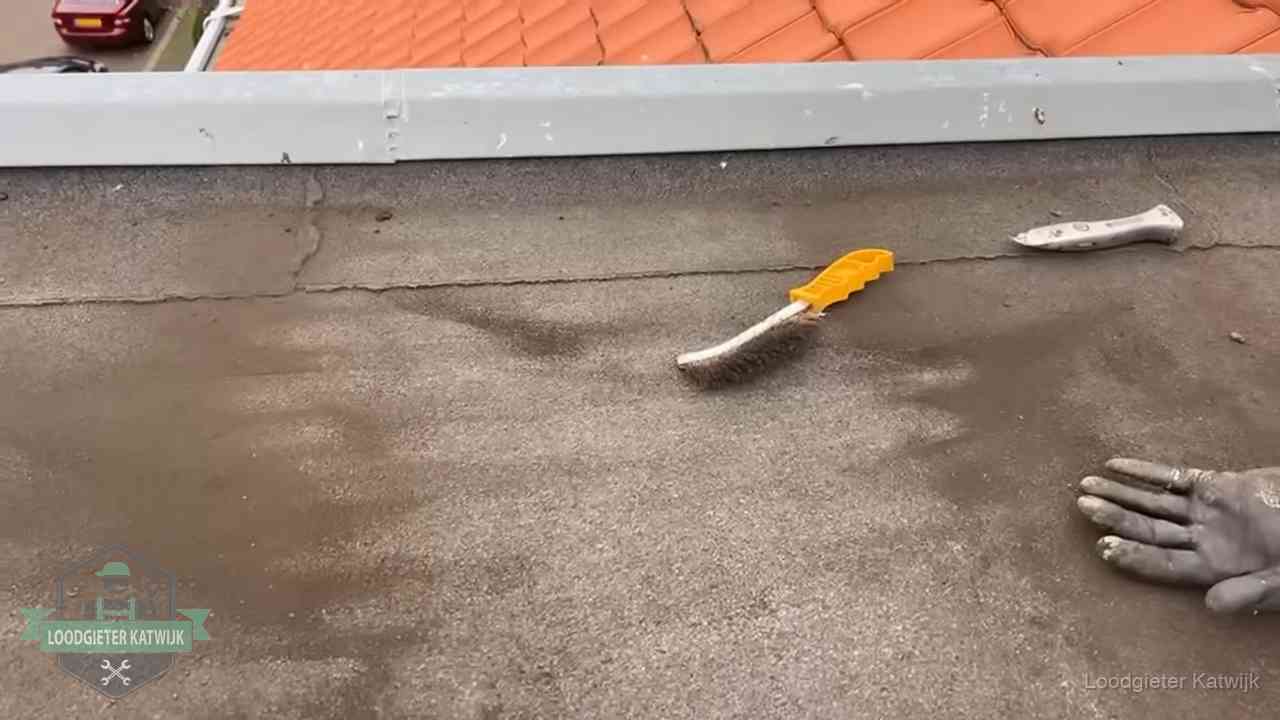 Kosten van daklekkage-reparatie in Katwijk Dakdekker bereidt een bitumen plat dak voor op reparatie bij de daktrim in Katwijk