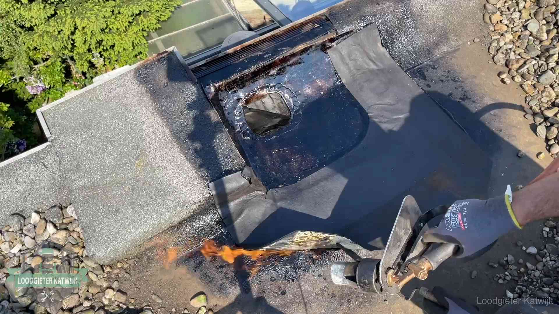 Daklekkage repareren in Katwijk Dakdekker brandt bitumen rond een doorvoer tijdens een daklekkage-reparatie in Katwijk