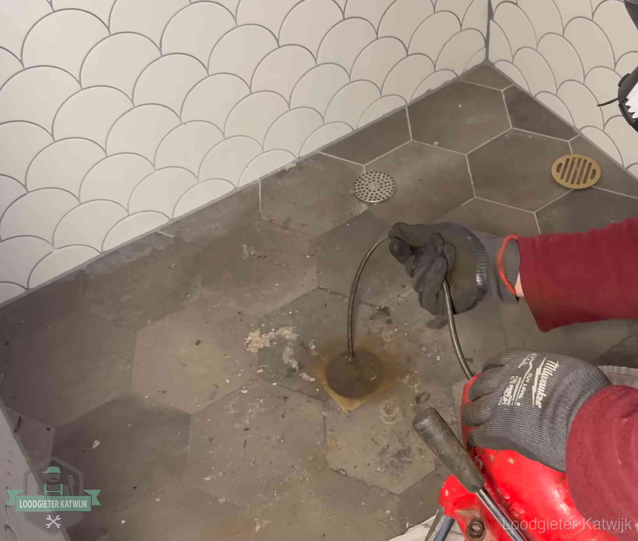 Ontstoppingsveer gaat in een geopend doucheputje in Katwijk waar het water omhoogkwam