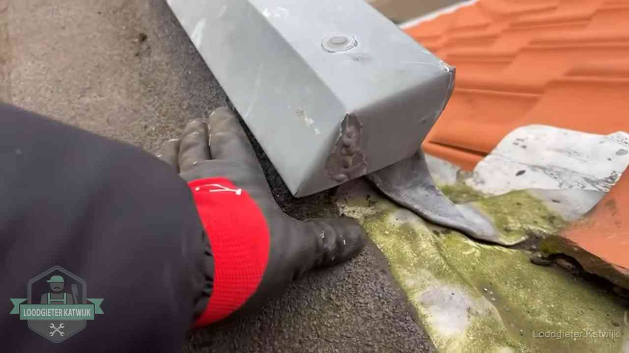 Hemelwaterafvoer en dakgoot controleren in Katwijk Controle van een zinken hemelwaterafvoer met loodslab bij dakpannen in Katwijk