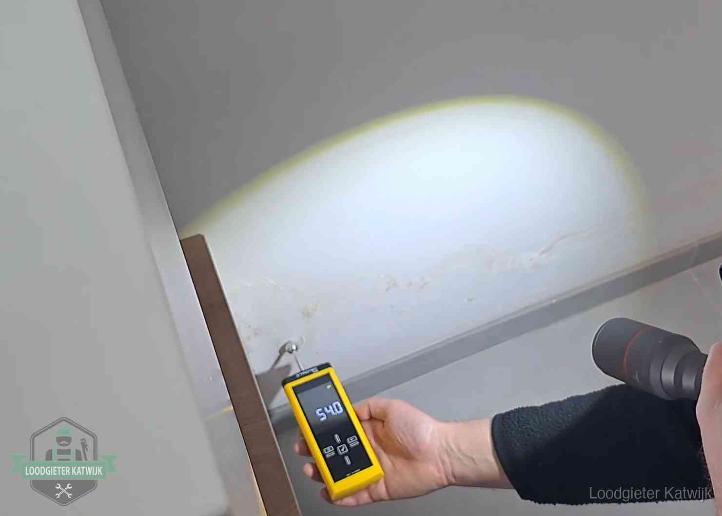 Vochtmeter tegen een natte wand met lekkagesporen in Katwijk