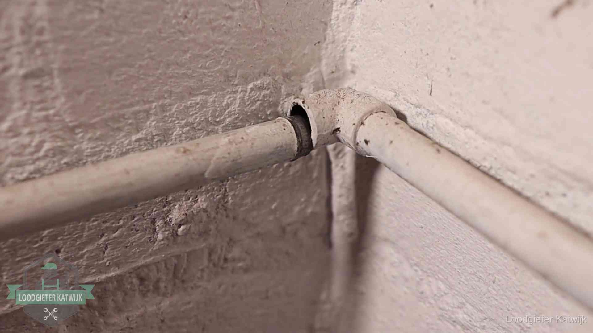 Oude geverfde waterleiding met een losliggende fitting in een woning in Katwijk