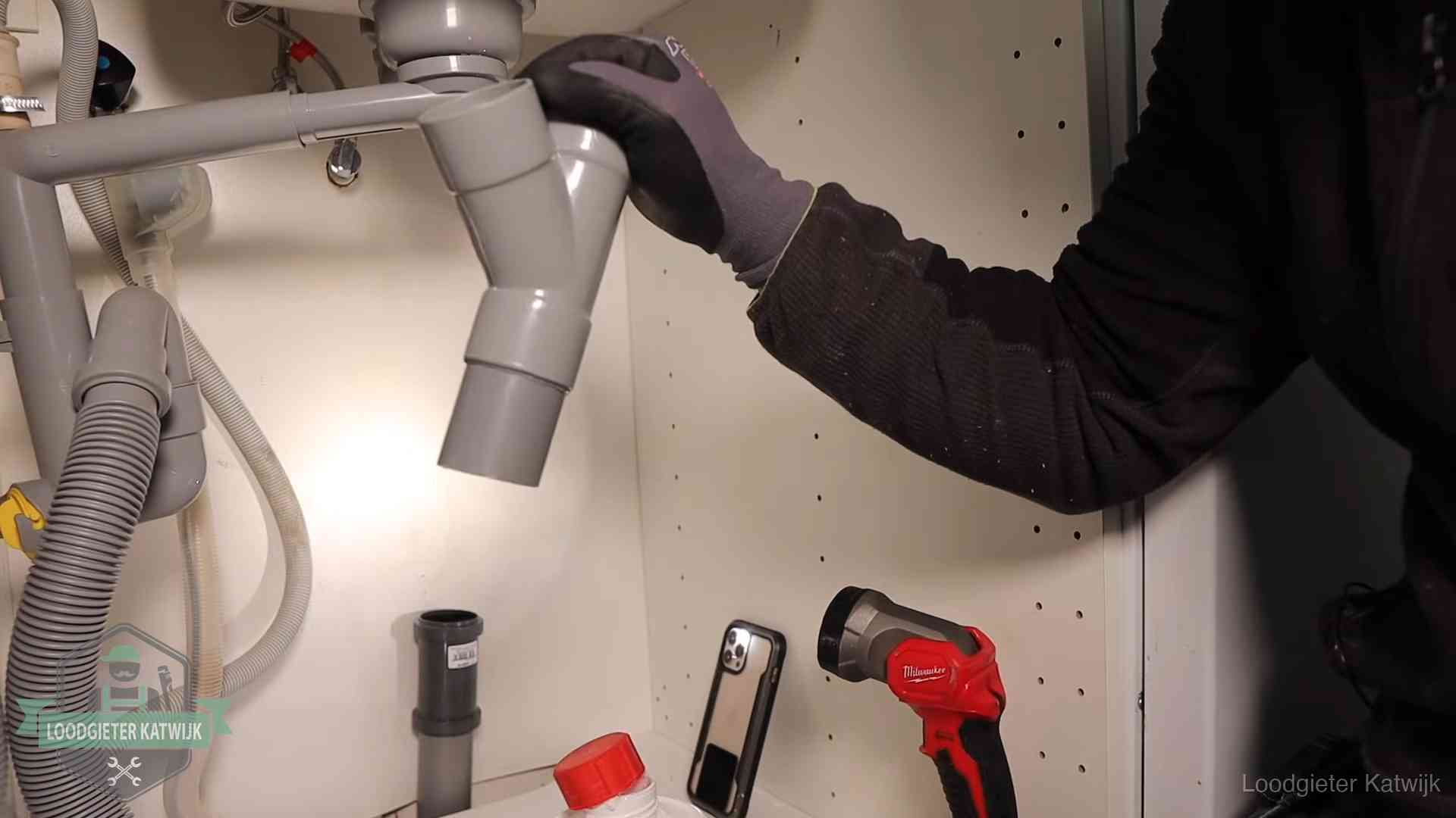 Loodgieter demonteert het sifon- en afvoerwerk onder een gootsteen in Katwijk bij stankklachten