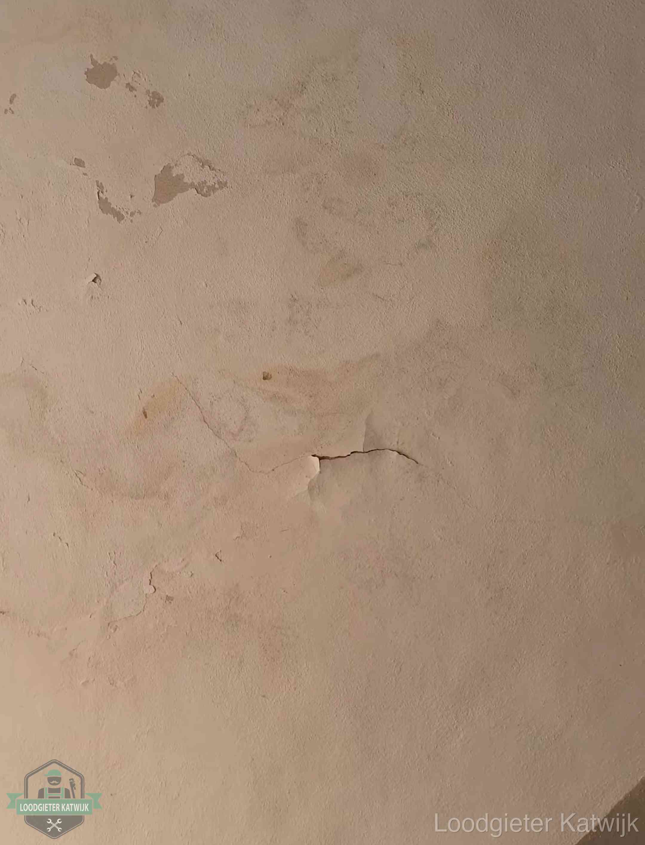 Vochtkringen en afbladderende verf op een plafond in Katwijk, schade voor het meetrapport en de verzekering